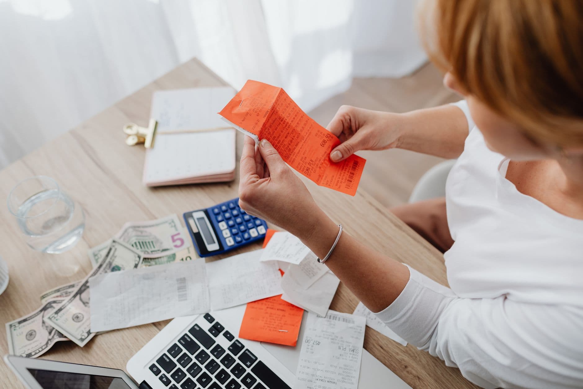Small business owner reviewing invoices, a calculator and a laptop at a desk