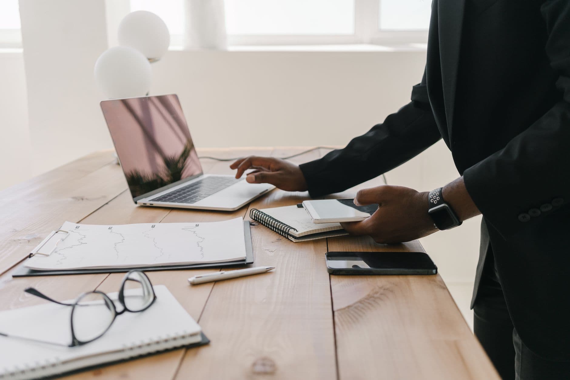 A desk with an open laptop, printed documents, a notebook and a phone during a working session